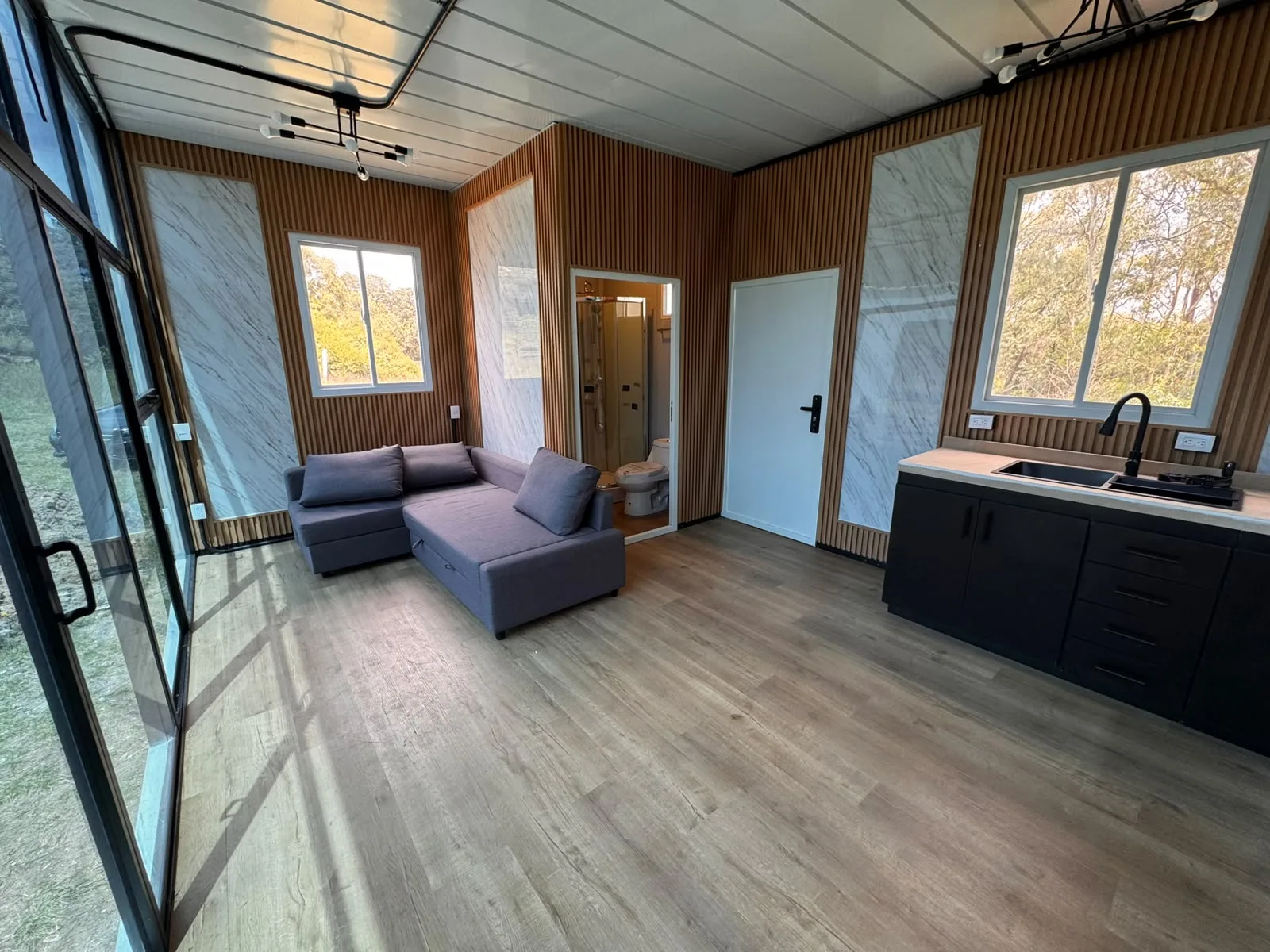 Interior de módulo terminado con sala, cocineta, baño y ventanal de piso a techo